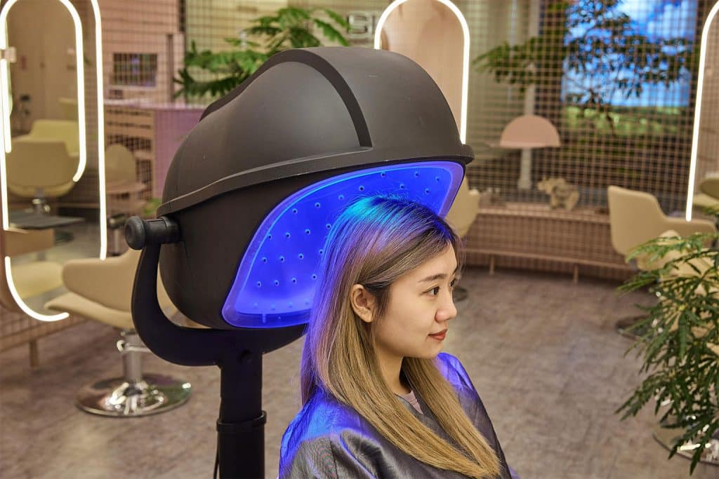 Client receiving blue light therapy after microneedling